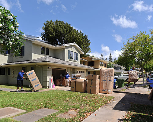 The front of a house with moving boxes and movers.